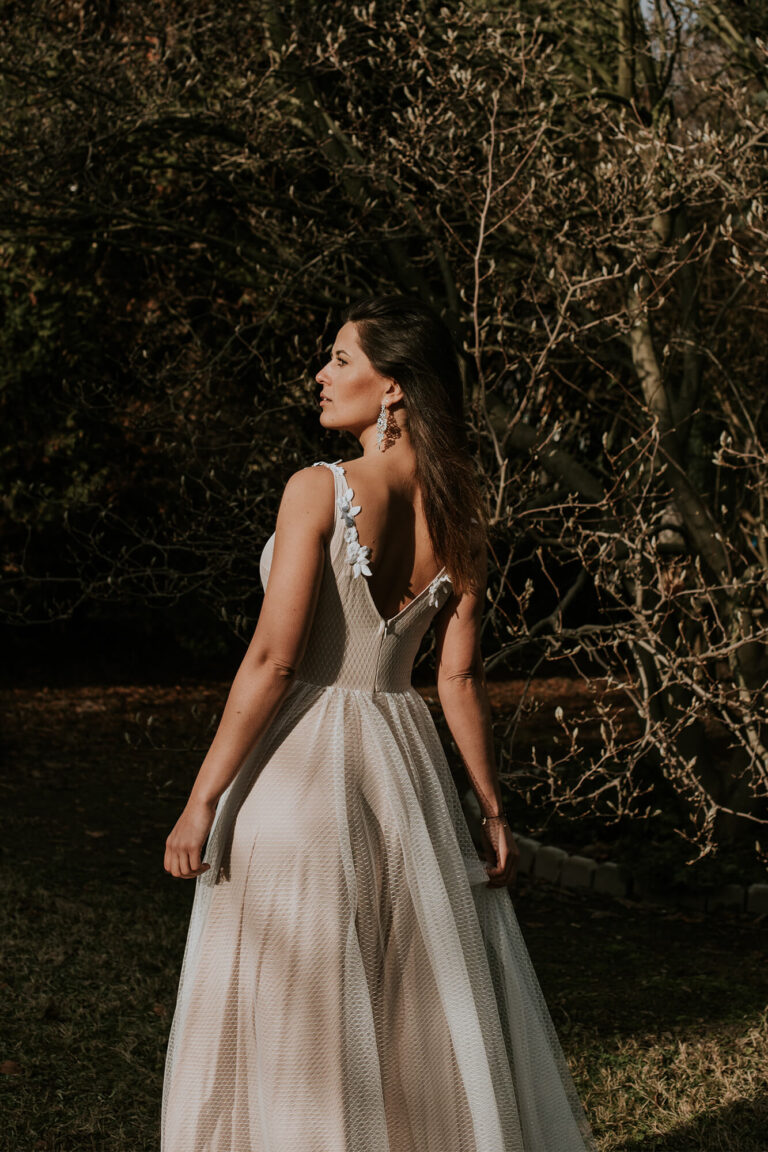 Suknia z odkrytymi plecami i cienkimi ramiączkami, widoczny długi tren.