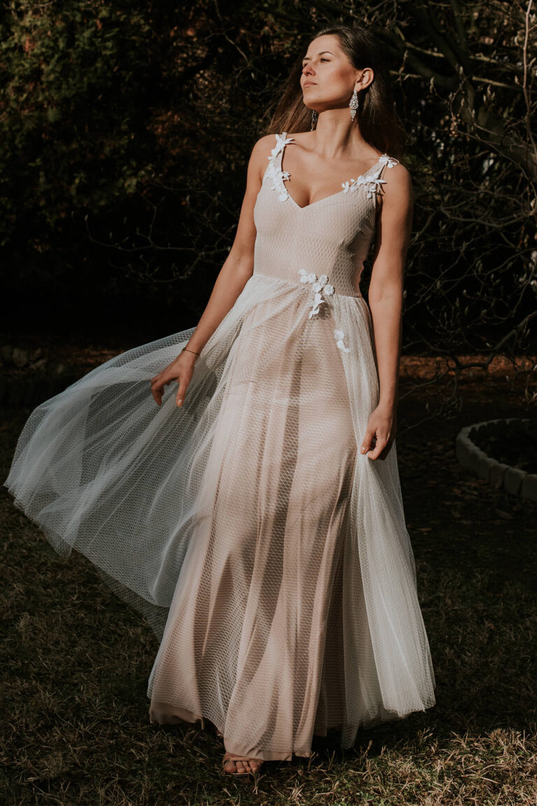 Suknia z tiulu z dekoltem w kształcie litery V i długim rozkloszowanym trenem.