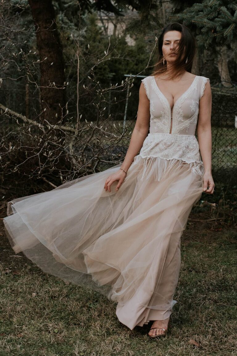 Suknia z dekoltem w serek, długim tiulowym trenem i koronkowymi detalami.