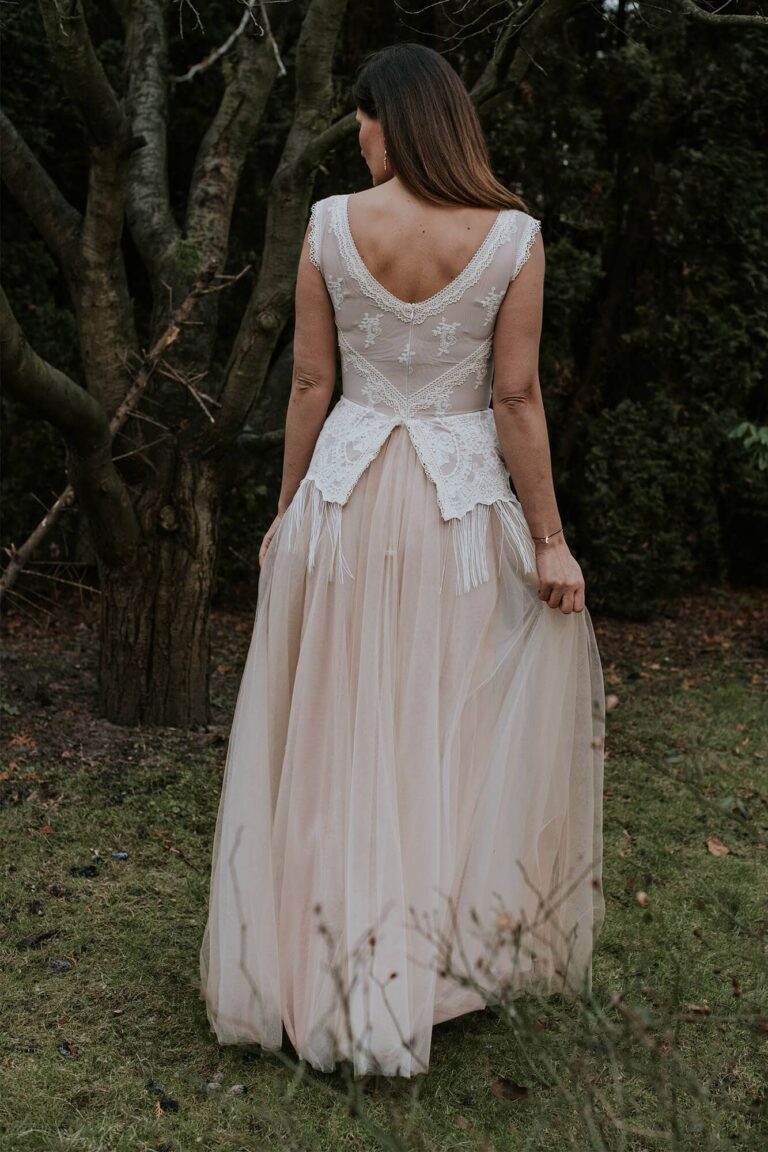 Suknia z odkrytymi plecami i długim rozkloszowanym dołem w kolorze jasnym.