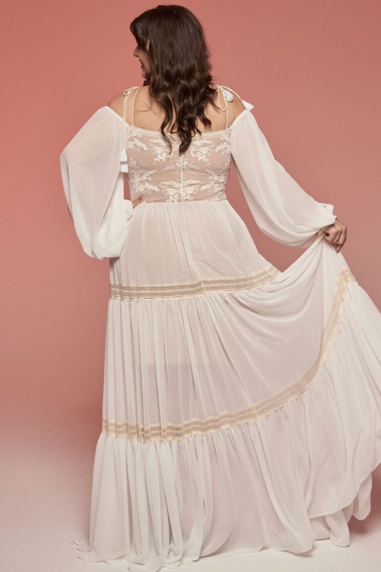 Suknia z długimi rękawami, odkrytymi plecami i falbanami na dolnej części.