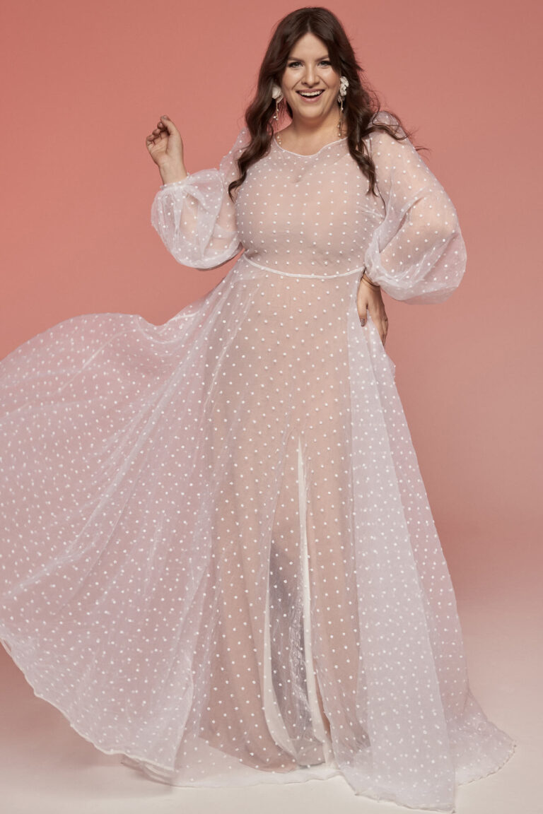 Suknia z długimi rękawami i rozkloszowanym dołem w kolorze różowym z półprzezroczystym materiałem.