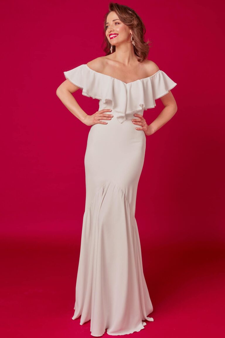Suknia z odkrytymi ramionami i falbaną na dekolcie, dopasowana do sylwetki.