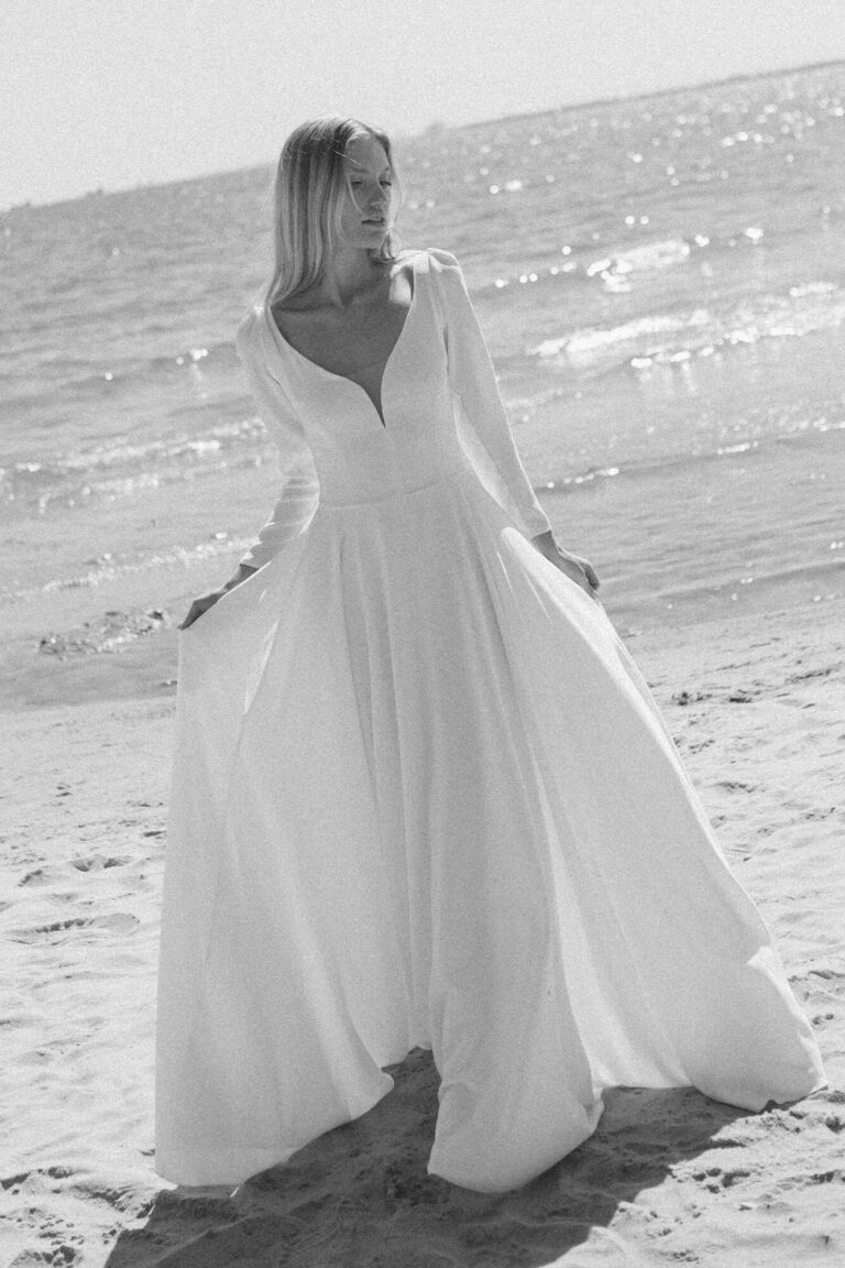 Suknia z długimi rękawami i odkrytym dekoltem, widoczna w całości.