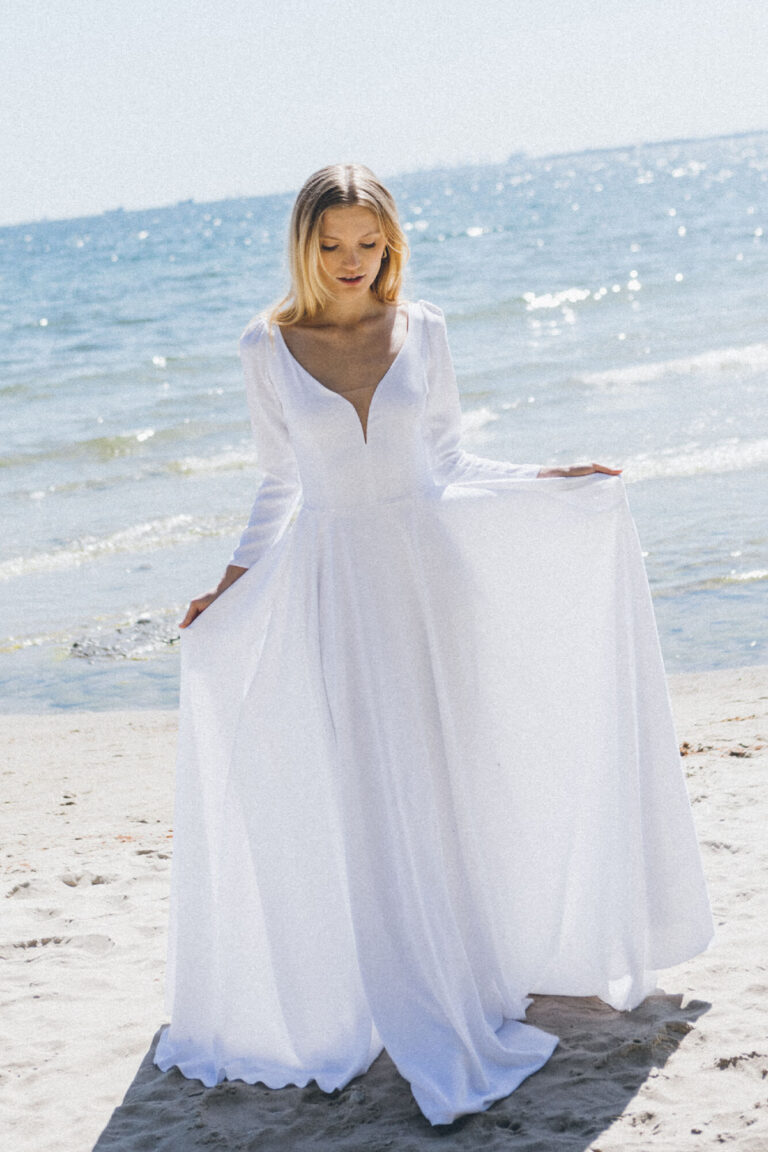 Suknia z długimi rękawami i dekoltem w kształcie litery V, z lekkim trenem.