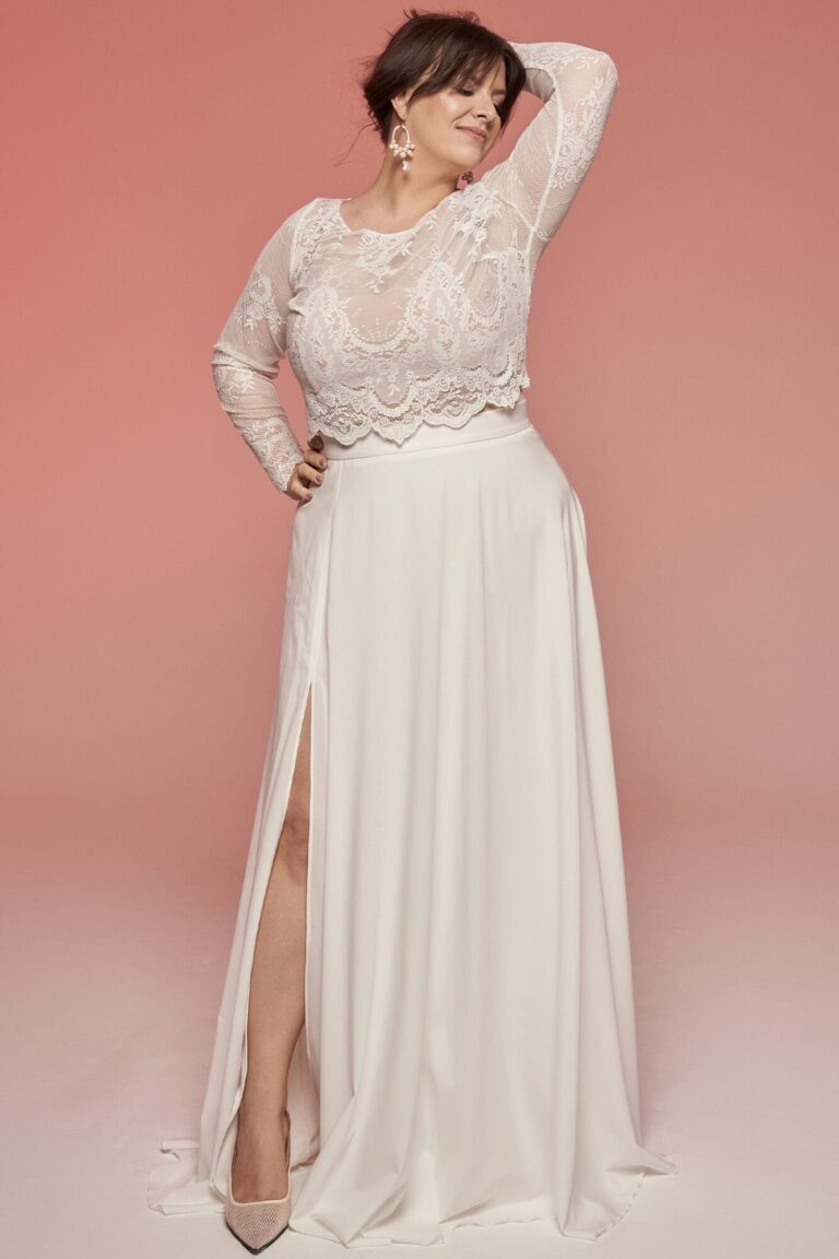 Suknia z długimi rękawami i rozcięciem z przodu, wykonana z materiału w kolorze białym.