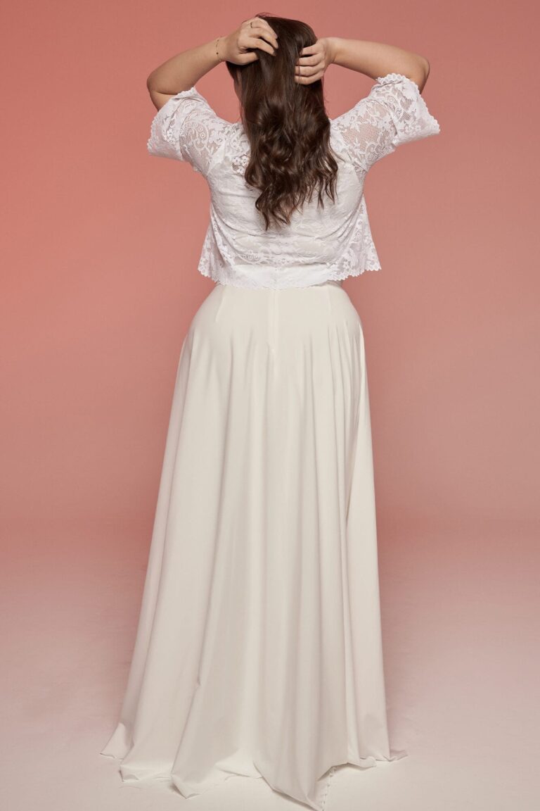 Suknia z długim, rozkloszowanym dołem i koronkowymi rękawami widziana z tyłu.