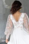Suknia ślubna z długimi koronkowymi rękawami i dekoltem w serek widziana z tyłu.