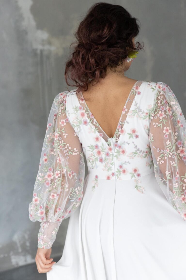 Suknia ślubna z długimi koronkowymi rękawami i dekoltem w serek widziana z tyłu.