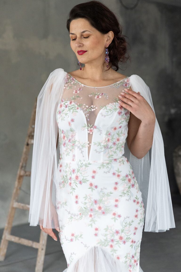 Suknia ślubna z koronkowym dekoltem, długimi rękawami i haftem kwiatowym.