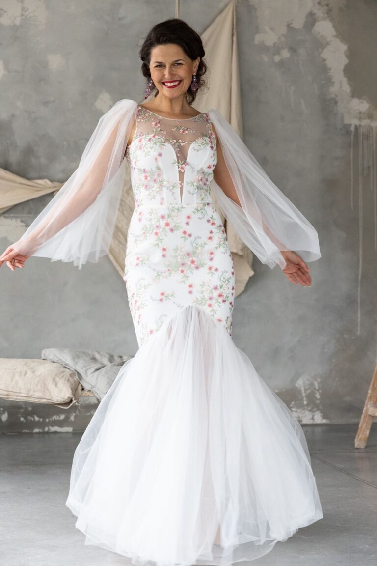 Suknia ślubna z długimi koronkowymi rękawami i dopasowanym krojem.