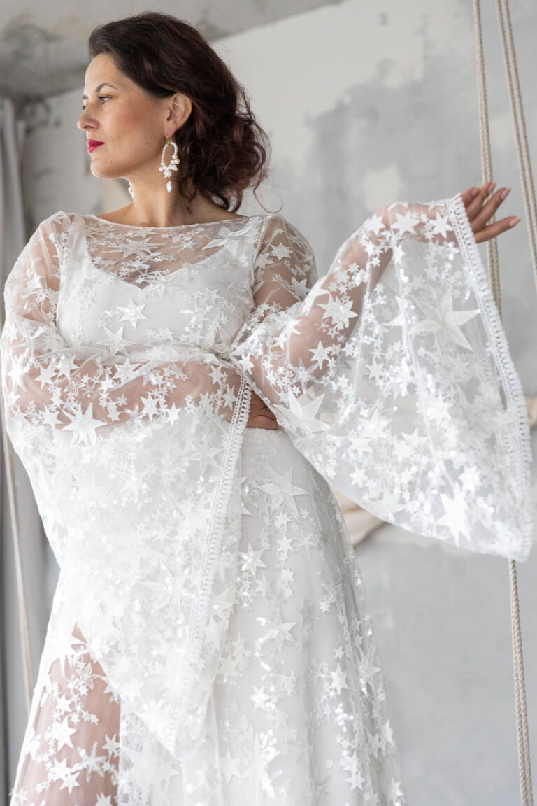 Suknia ślubna z długimi koronkowymi rękawami i odkrytymi plecami.