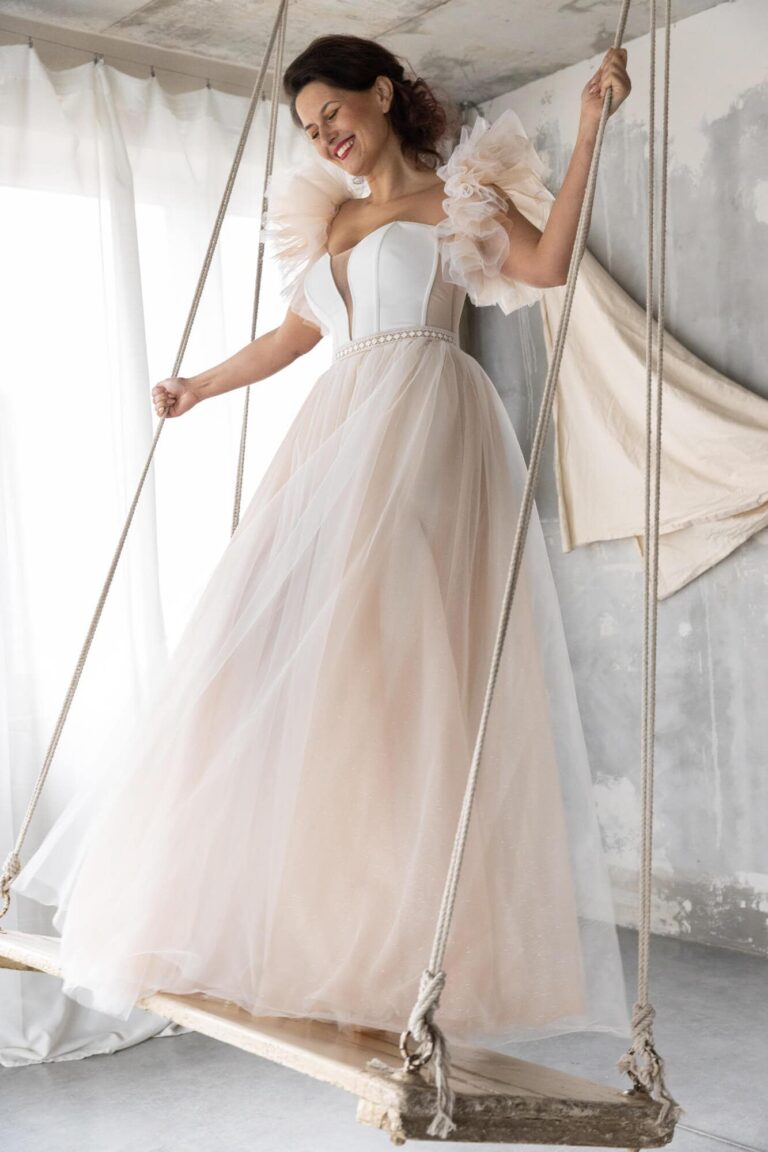 Suknia z tiulu z odkrytymi plecami i bufkowymi rękawami.