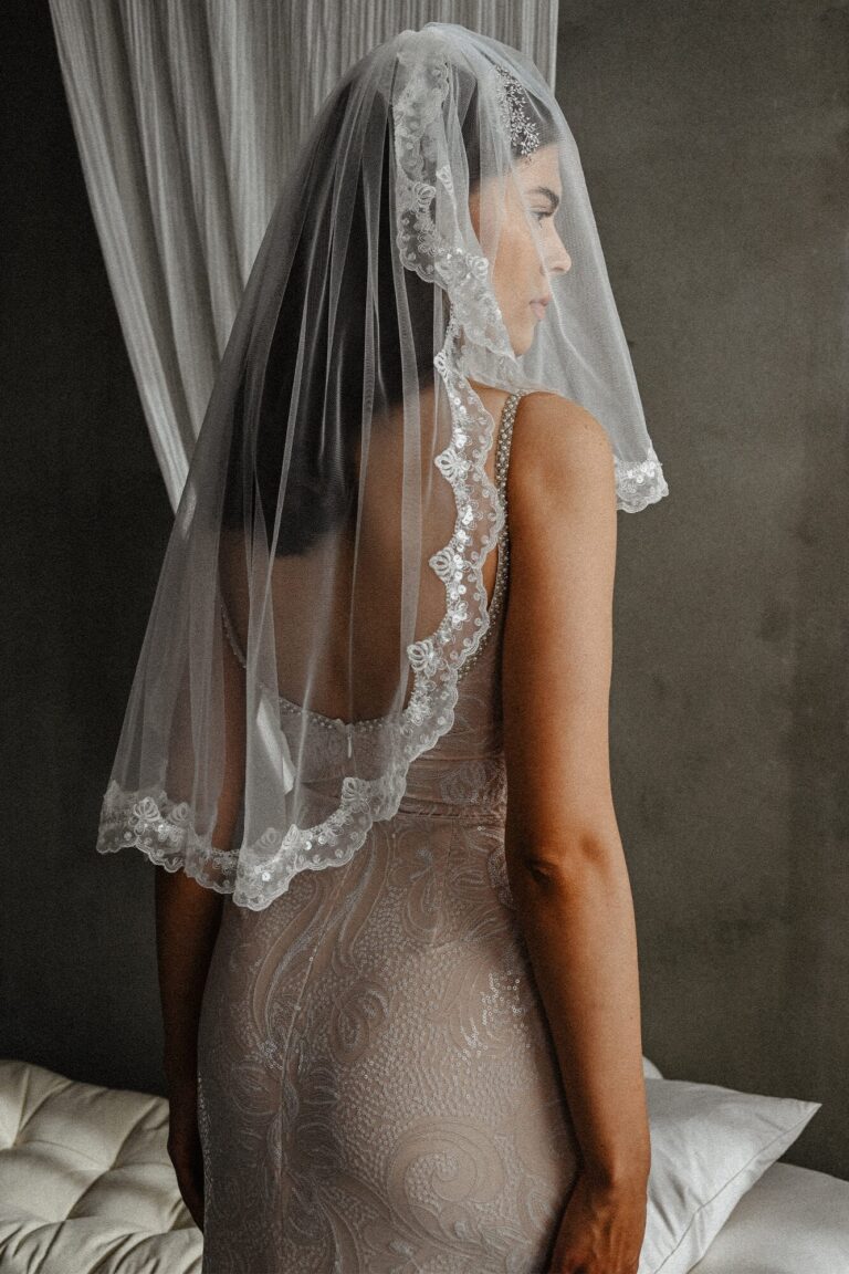 Suknia z odkrytymi plecami i welonem z koronkowym wykończeniem.