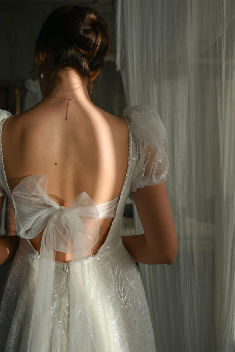 Suknia ślubna z odkrytymi plecami i krótkimi rękawami z tiulu.