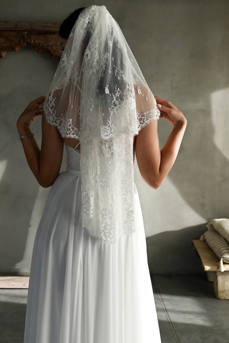 Suknia ślubna z odkrytymi plecami i długim welonem z koronką.