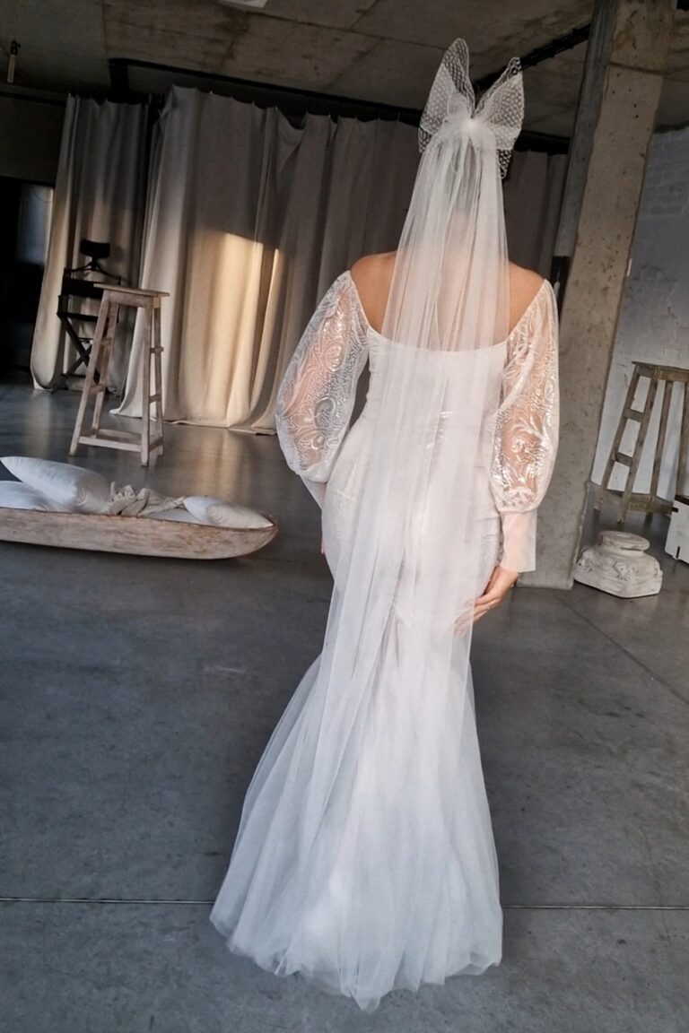 Suknia ślubna z długimi koronkowymi rękawami i trenem widoczna z tyłu.