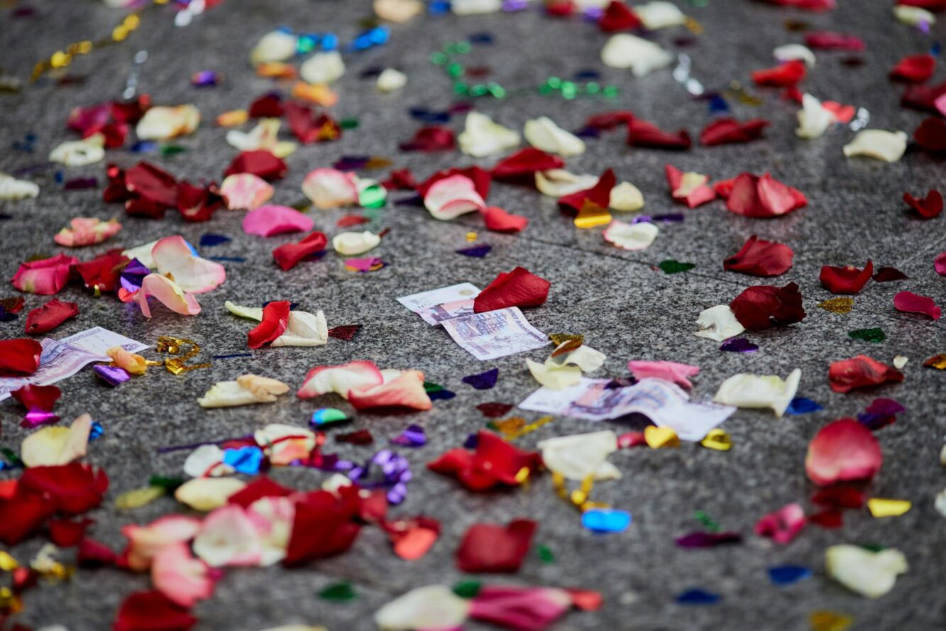 Płatki róż i kolorowe konfetti leżą na szarej nawierzchni.