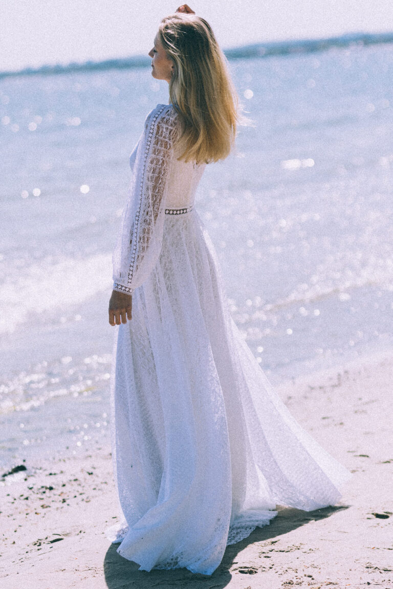 Suknia z długimi rękawami i przezroczystym trenem widoczna z tyłu.