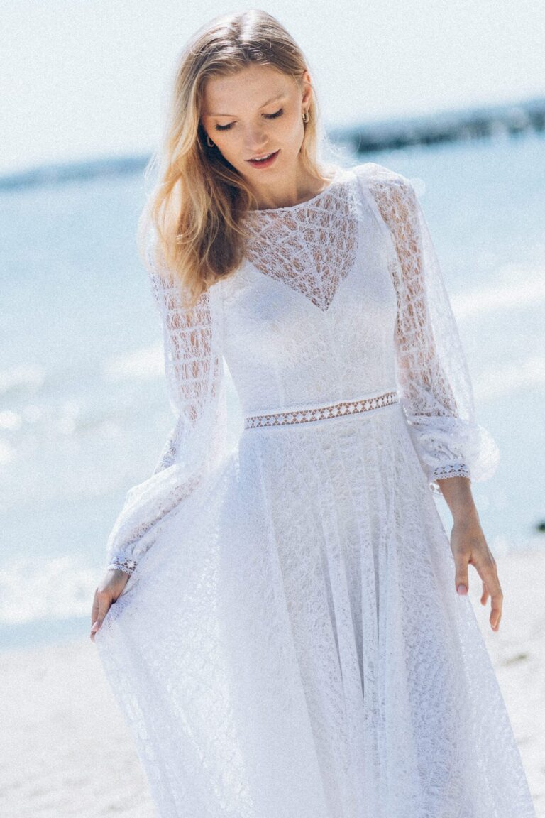 Suknia z długimi koronkowymi rękawami i rozkloszowanym dołem.
