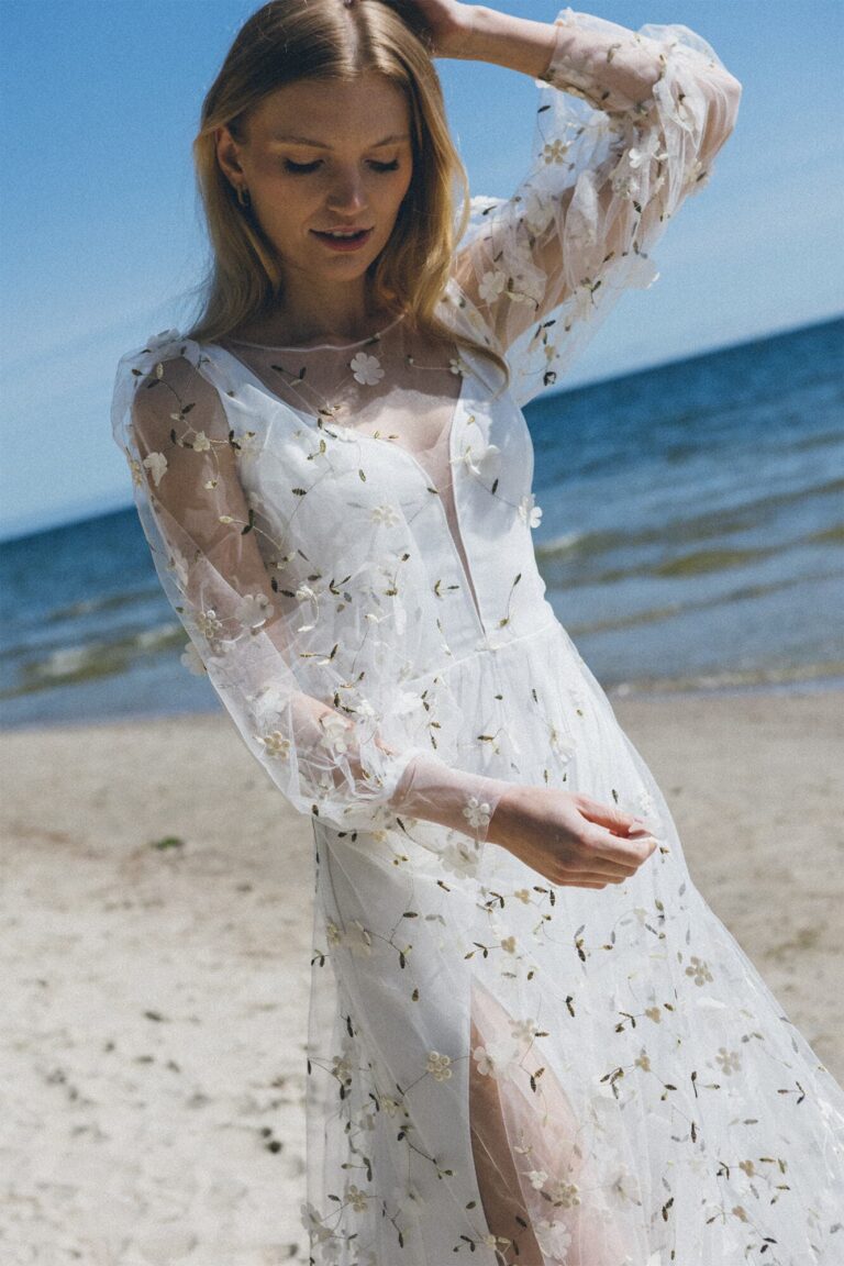 Suknia z długimi koronkowymi rękawami i rozcięciem z przodu.