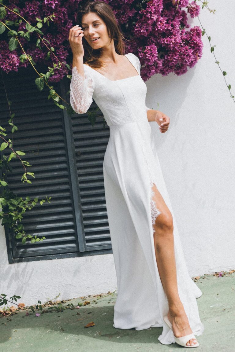 Suknia z długimi rękawami, dekoltem i rozcięciem na nogawce.