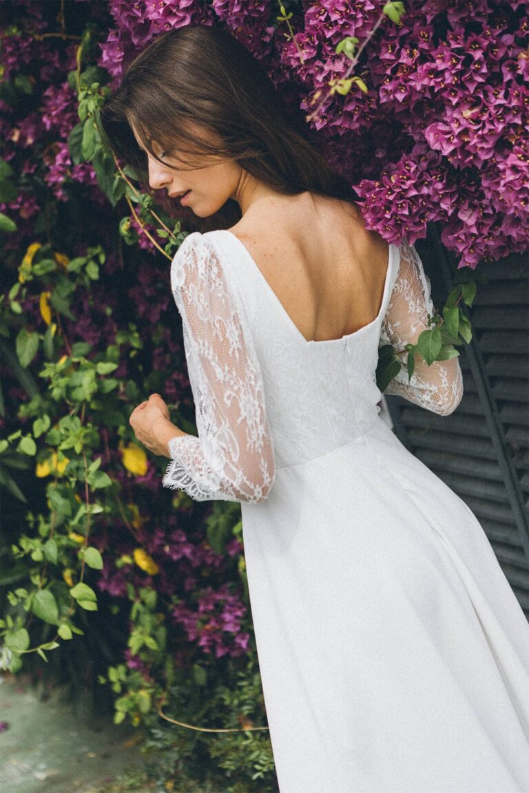 Suknia z odkrytymi plecami i długimi koronkowymi rękawami.