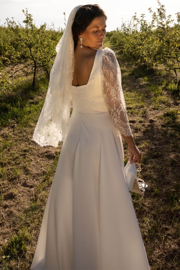 Suknia ślubna z długimi koronkowymi rękawami i dekoltem w kształcie litery V.