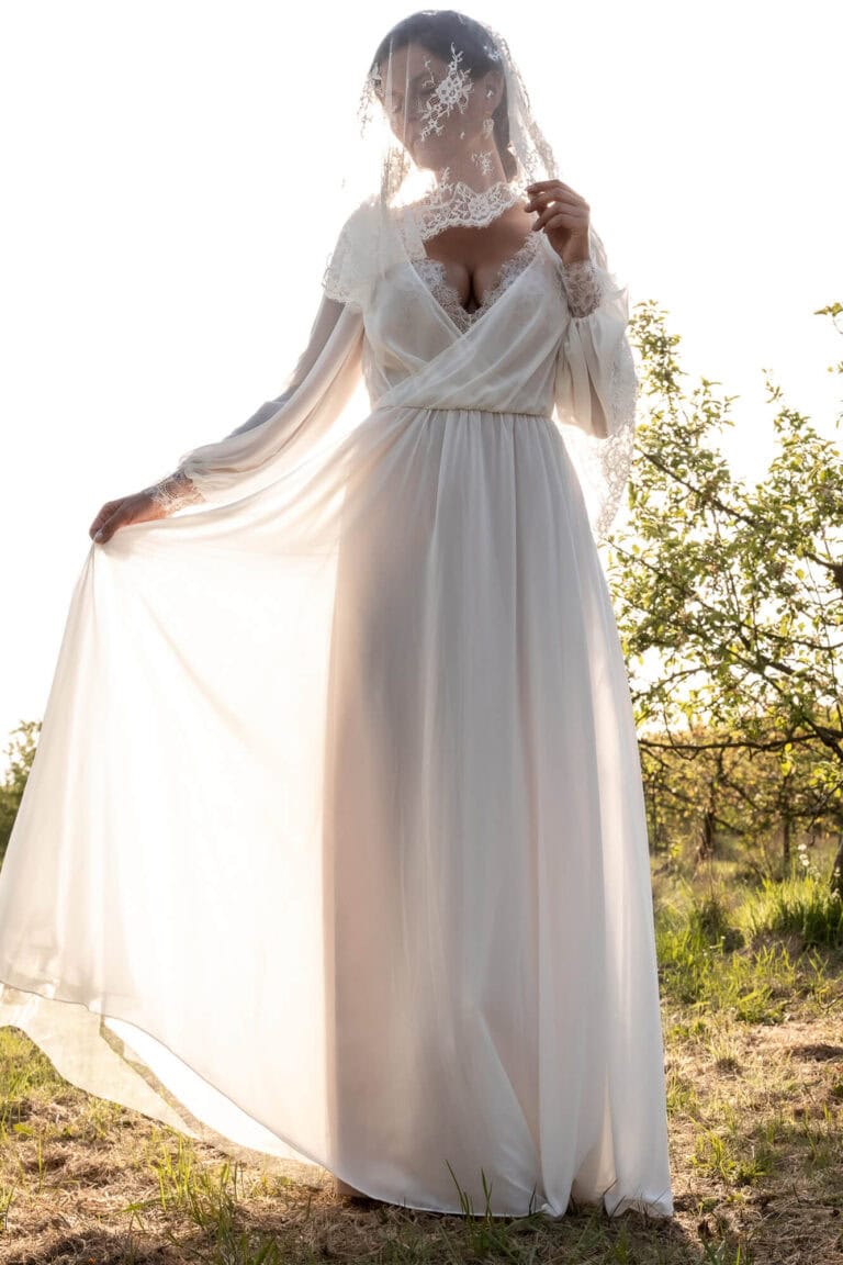 Suknia ślubna z długim tiulowym trenem i odkrytymi ramionami.