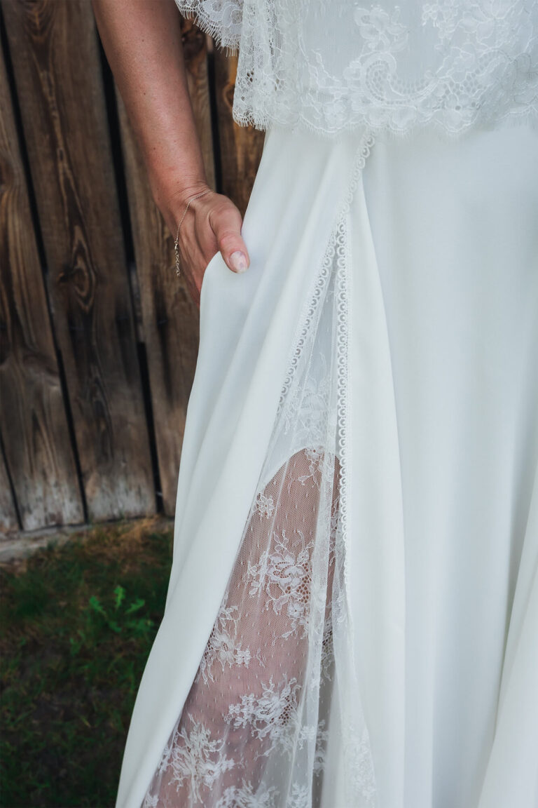 Suknia ślubna z koronkowym wykończeniem i rozcięciem odsłaniającym nogę.