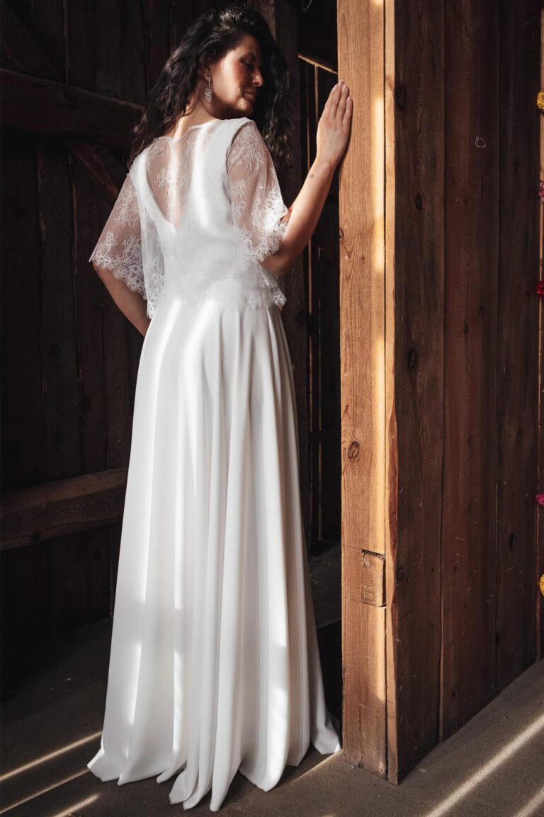 Suknia ślubna z długimi rękawami i odkrytymi plecami w kolorze białym.