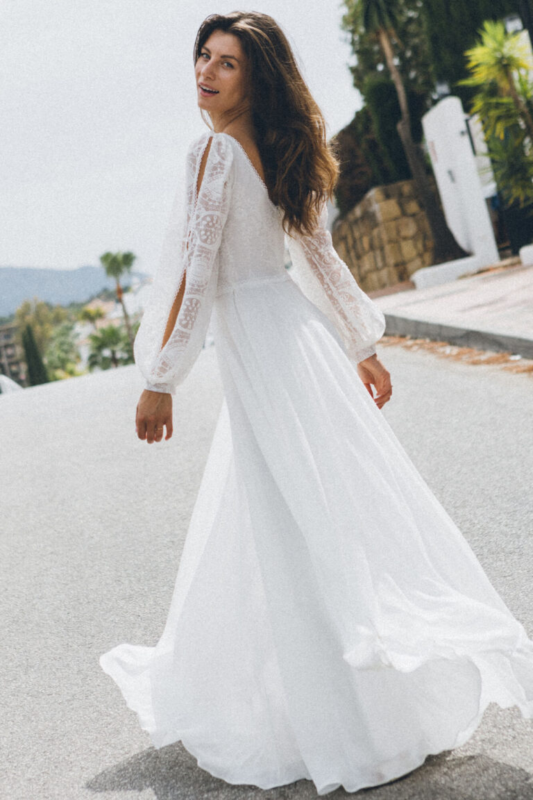 Suknia z długimi rękawami i rozkloszowanym dołem widoczna z tyłu.