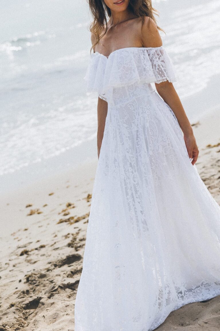 Suknia z odkrytymi ramionami i długim, zwiewnym dołem w kolorze białym.