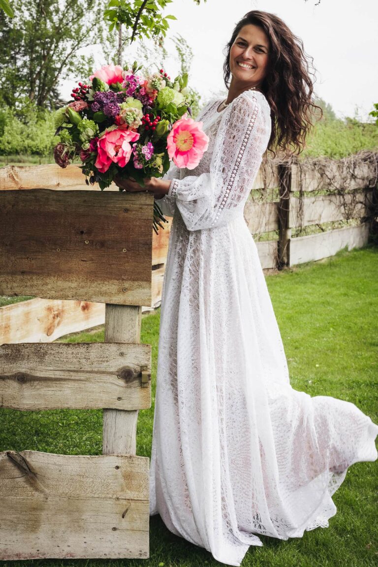 Suknia z długimi rękawami i rozkloszowanym dołem, widoczna w ogrodzie.