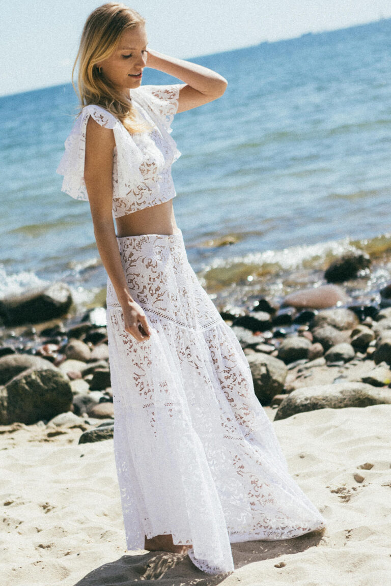 Suknia ślubna z koronkowymi rękawami i długim, przezroczystym dołem.