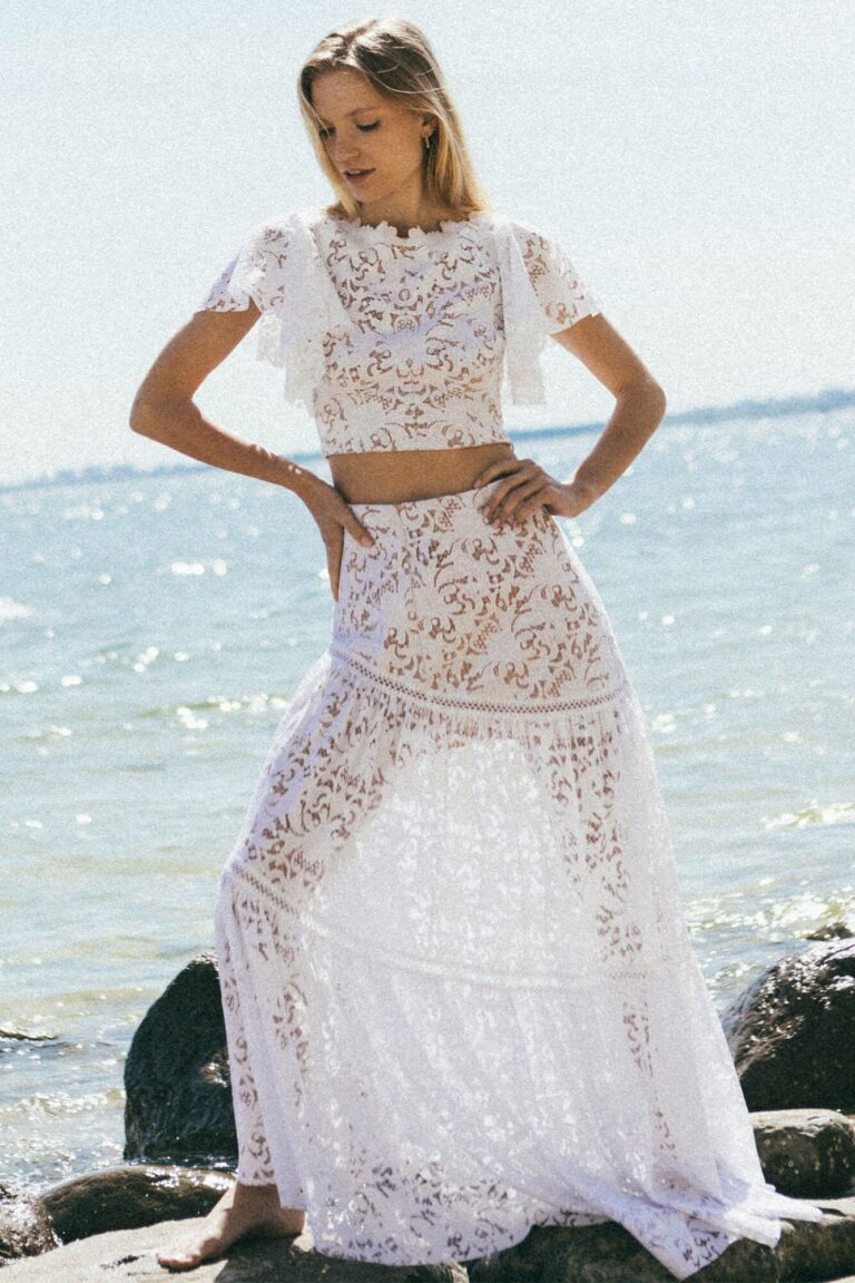 Suknia z koronkowymi rękawami i rozkloszowanym dołem widoczna z przodu.