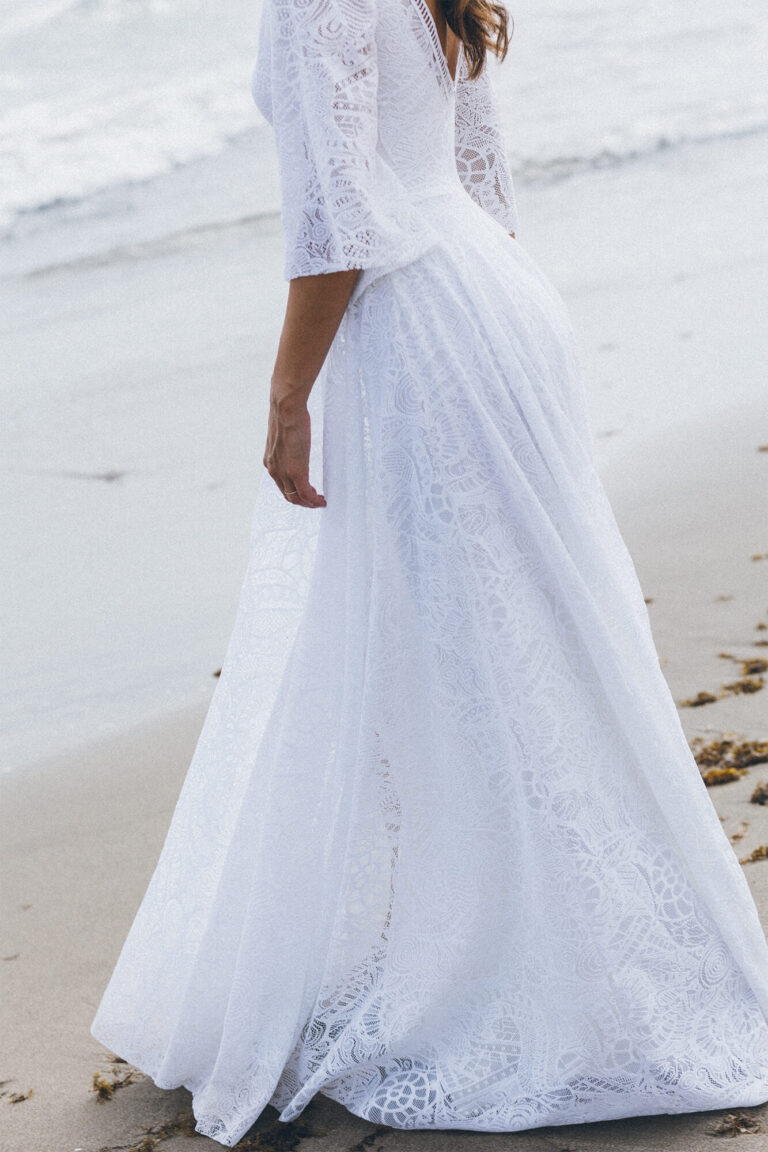 Suknia z długimi rękawami i rozkloszowanym dołem widziana z boku.