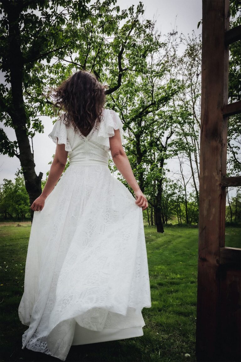 Suknia ślubna z odkrytymi plecami i krótkimi rękawami, widziana z tyłu.