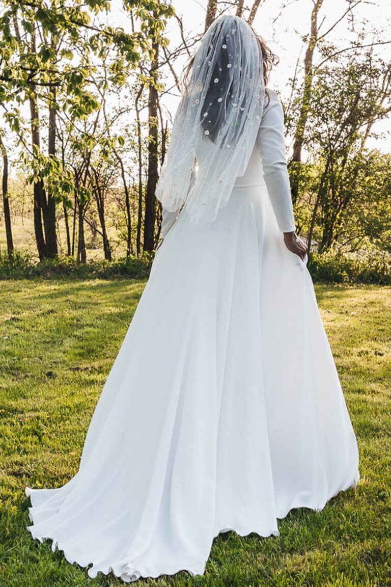 Suknia ślubna z długimi rękawami i odkrytymi plecami widziana z tyłu.