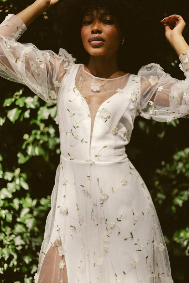 Suknia z długimi koronkowymi rękawami i głębokim dekoltem z rozcięciem na przodzie.