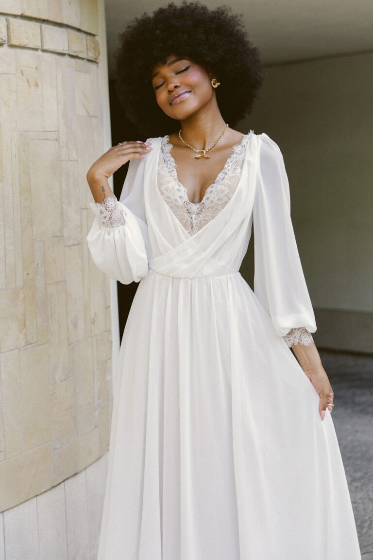 Suknia z długimi rękawami i dekoltem w serek, widoczna w całości.