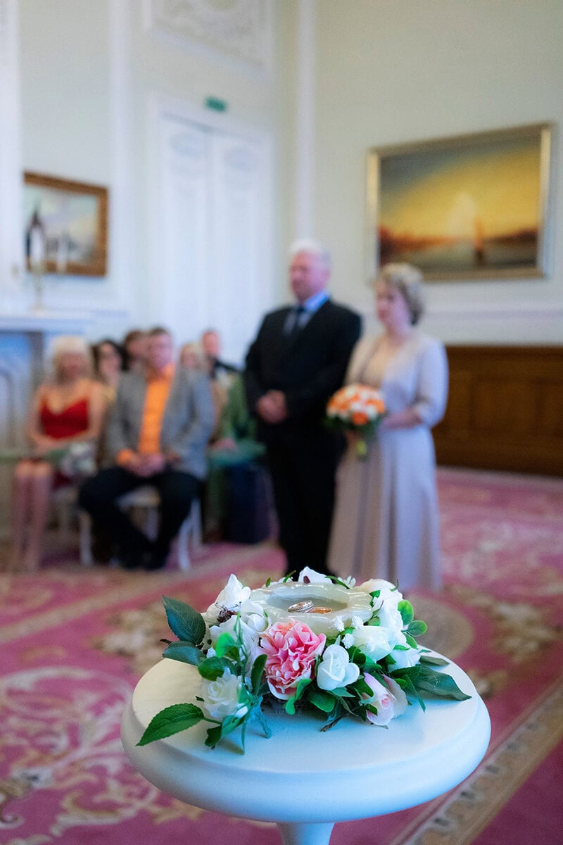 Ceremonia ślubu cywilnego z obrączkami na stole ozdobionym kwiatami.