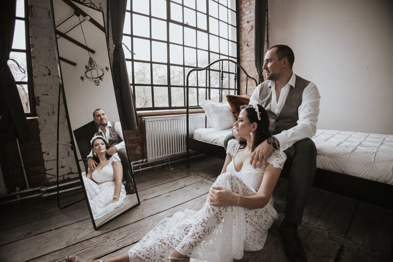 Para w eleganckiej scenerii, kobieta w koronkowej sukni.
