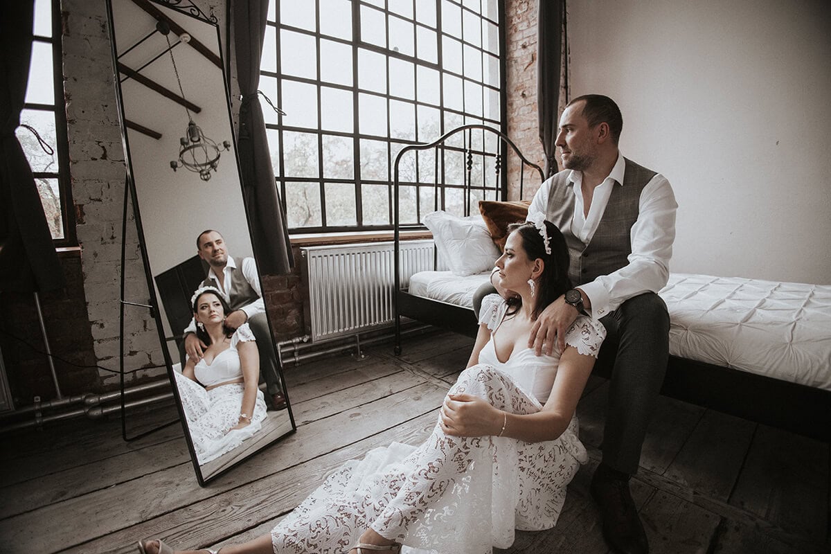 Para w eleganckiej scenerii, kobieta w koronkowej sukni.