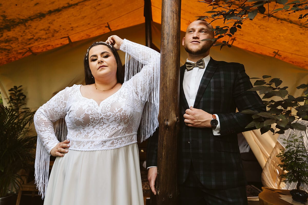 Para w eleganckich strojach, suknia ślubna z koronką i frędzlami.