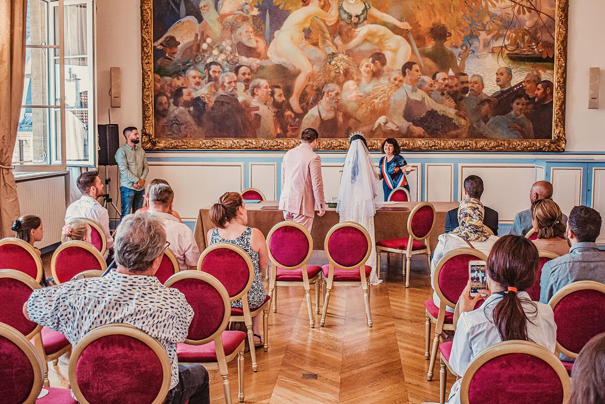 Ceremonia ślubu cywilnego w sali z dużym obrazem na ścianie.